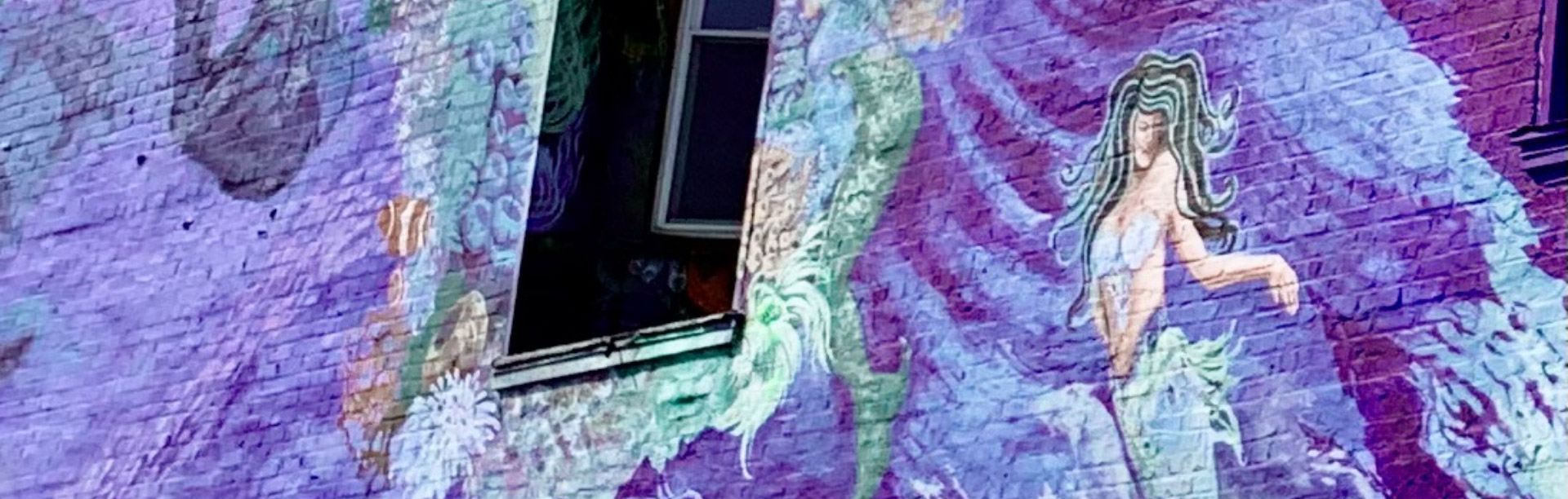 Photo of a mural on a brick wall with a painting of a mermaid